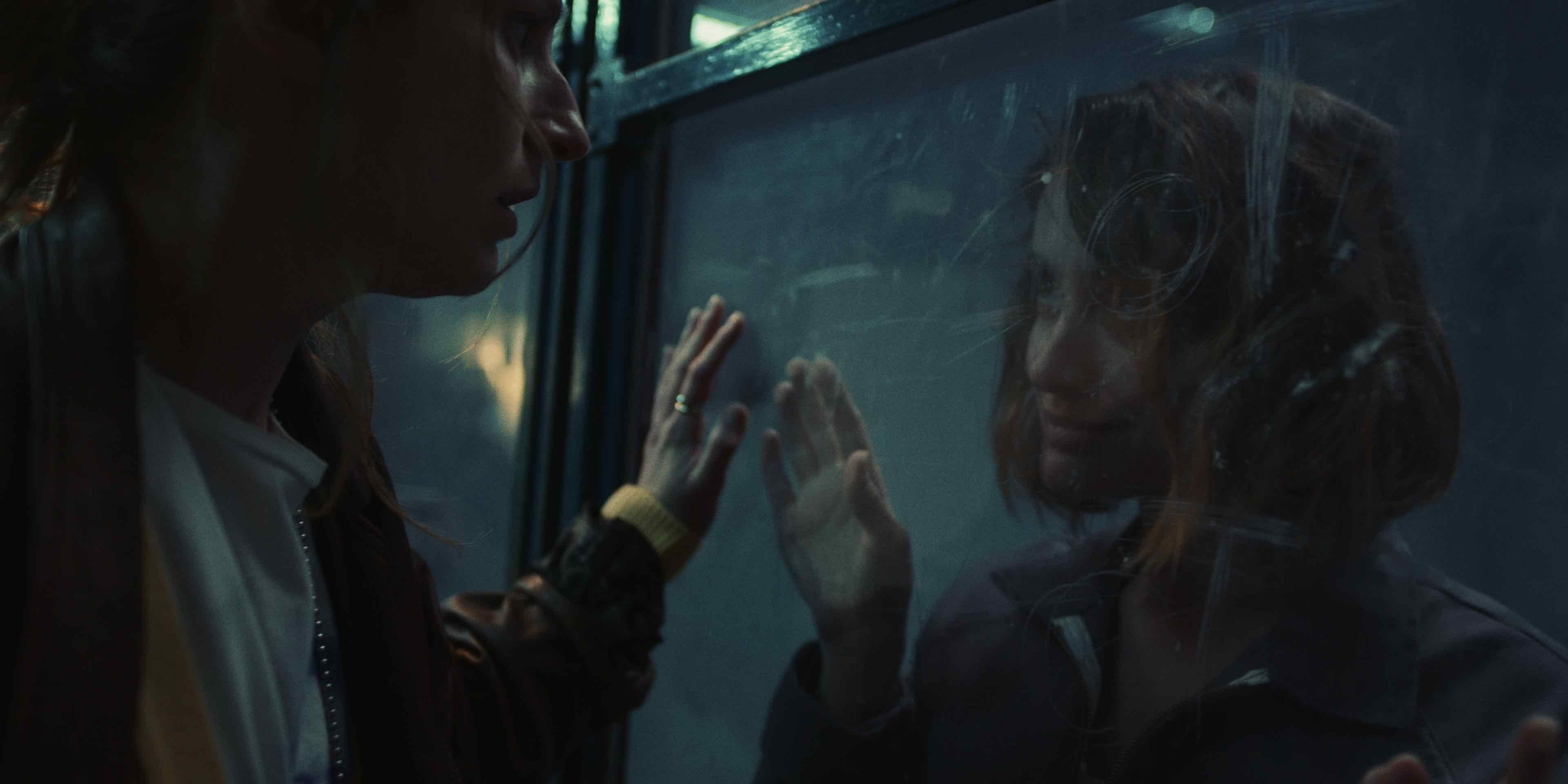 Two women talking through a glass window